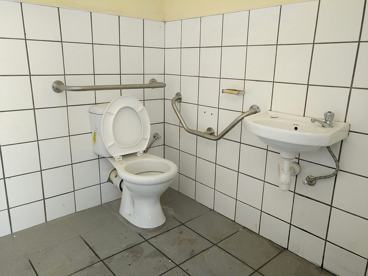 Accessible tiled bathroom with grab rails, toilet and basin